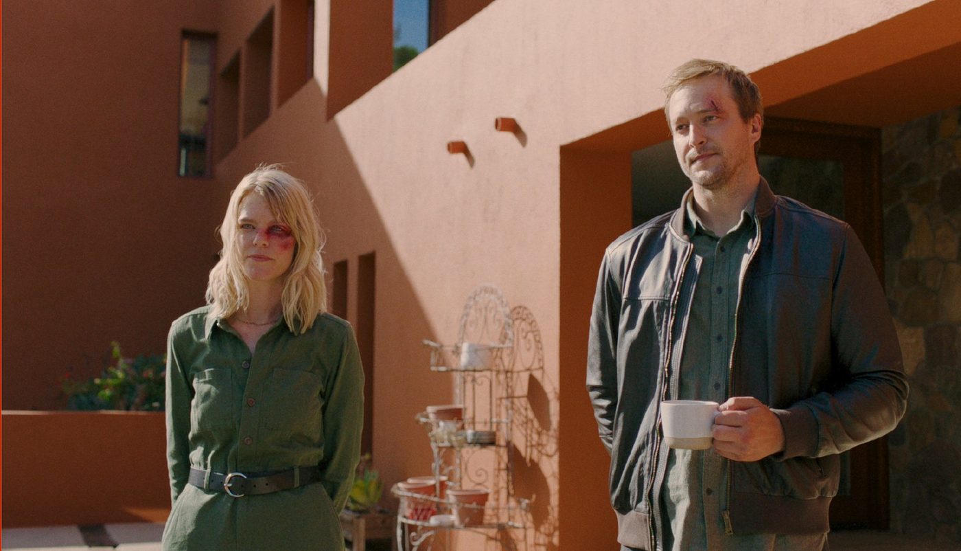 Claire and Vince, bruised, stand outside the terracotta house with coffee